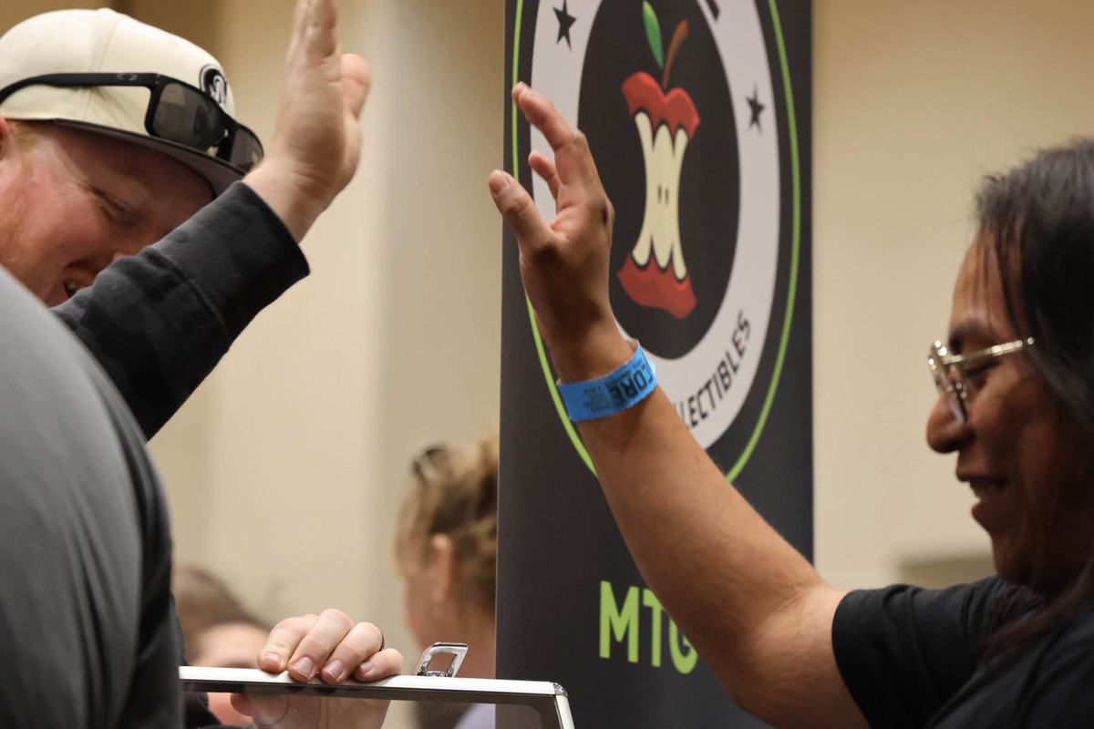 Two attendees high-five beside a Core Cards event banner